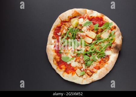 Pizza avec jambon fumé et rucola sur fond noir. Vue de dessus. Pizza savoureuse avec viande sur sol sombre Banque D'Images