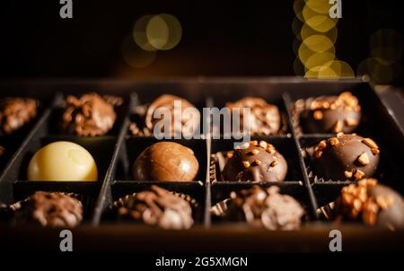 Délicieuses bonbons au chocolat ou boulettes de truffe dans une boîte sur la table contre le bokeh léger. Assortiment de pralines au chocolat.assortiment de chocolats fins en blanc Banque D'Images