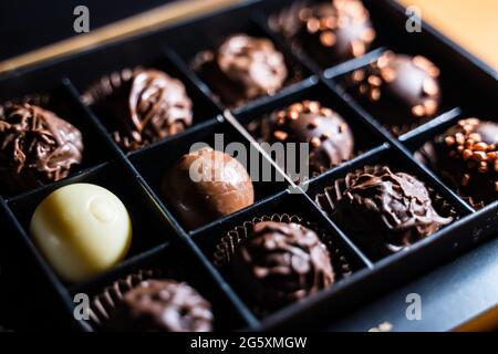 Plusieurs variétés de truffes au chocolat au chocolat et glaçure laiteuse et saupoudrer d'or avec des noix. Coupe de la boule de truffe ronde dans une boîte carrée. Banque D'Images