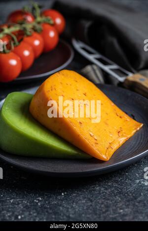 Bloc de fromage fort au piment et au wasabi sur une assiette noire. Banque D'Images