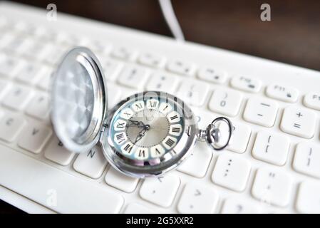 La montre de poche vintage antique repose sur un clavier blanc. Le concept de modernité, de fabricabilité, d'archaïsme, d'obsolescence Banque D'Images