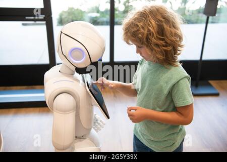 un petit garçon intelligent communique avec la technologie d'assistant robot pour l'éducation moderne, la robotique Banque D'Images