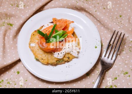 Crêpes de pommes de terre avec du poisson rouge sur le dessus et des oignons verts. Une partie. Petite plaque. Banque D'Images