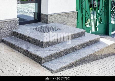 porche gris en granit avec un tapis de pied à l'entrée de la porte centrale en verre architecture moderne bureau de style étroit avec portail vert, n Banque D'Images