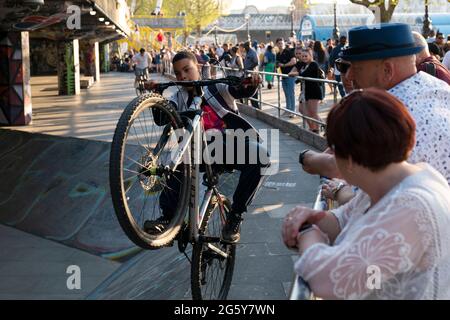 Les garçons font des cascades à vélo tandis que les touristes regardent sur Southbank Skate Space à Londres, Royaume-Uni Banque D'Images