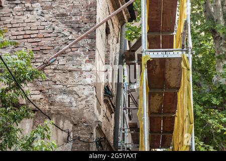 Photo d'une maison endommagée protégée par des échafaudages avant une opération de reconstruction ou de démolition en milieu urbain. Banque D'Images