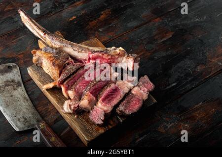 Set traditionnel de steaks de tomahawk de Wagyu vieux et sec, sur un plateau de service en bois, sur un arrière-plan de table en bois foncé, avec espace pour le texte Banque D'Images