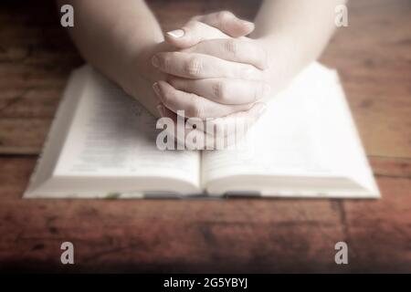 Une femme priant avec ses mains se replia sur sa Bible Banque D'Images