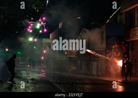 Bogota, Colombie. 28 juin 2021. Un feu d'artifice est tiré derrière les officiers de police anti-émeutes de Colombie alors que des manifestations antigouvernementales se manifestent en heurtant des manifestants et la police anti-émeute de Colombie (ESMAD), au milieu des tensions politiques contre le gouvernement du président Ivan Duque, des cas de brutalité policière et des inégalités alors que la Colombie marque un deuxième mois de manifestations anti-gouvernementales, à Bogota, Colombie le 28 juin 2021. Crédit : long Visual Press/Alamy Live News Banque D'Images