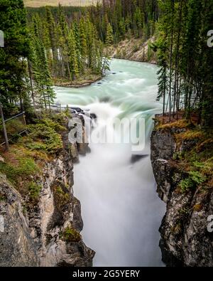 Exposition prolongée photo de l'eau turquoise de la rivière Sunwapta qui descend des chutes Sunwapta dans le parc national Jasper, dans le mont Rocky canadien Banque D'Images