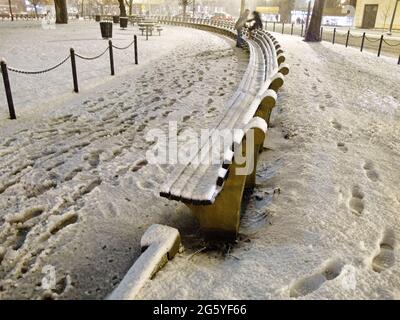 Un couple monte sur un banc de parc enneigé. Banque D'Images