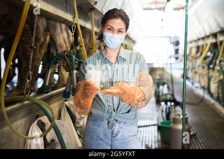 Femme en masque travaillant à la ligne de traite Banque D'Images