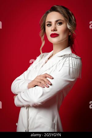 Portrait de femme blonde noble avec maquillage permanent parfait en blouson blanc debout tenant les bras croisés à la poitrine Banque D'Images