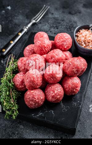 Boulettes de viande crues de bœuf haché et de viande de porc au thym. Arrière-plan en bois. Vue de dessus Banque D'Images