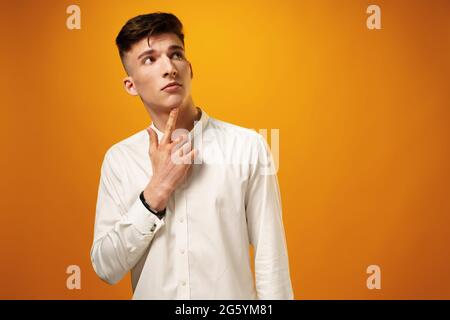 Portrait d'un jeune homme réfléchi qui regarde loin de toucher son menton Banque D'Images