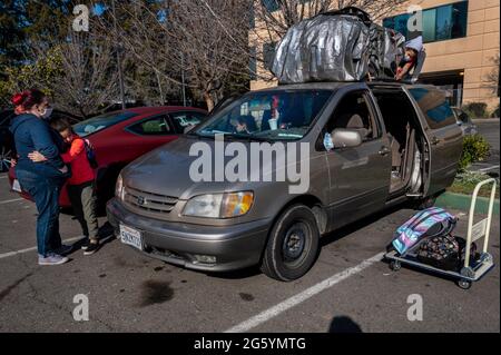 Sacramento, Californie, États-Unis. 17 janvier 2021. Tiree Franklin, 11 ans, aide à attacher ses effets personnels de famille sur leur camionnette alors que sa mère Kristi Phillips, 47 ans, console la fille Aryanna Slain, 8 ans, comme une autre fille Shyann Slain, 7 ans, attend à l'intérieur de la camionnette le samedi 17 janvier 2021. La famille a été en train de quitter le Fairfield Inn et s'est dirigée vers un parc pour camper après avoir manqué d'argent pour payer une autre nuit. Ils sont sans abri depuis environ trois ans. (Credit image: © Renee C. Byer/The Sacramento Bee/ZUMA Press Wire) Banque D'Images