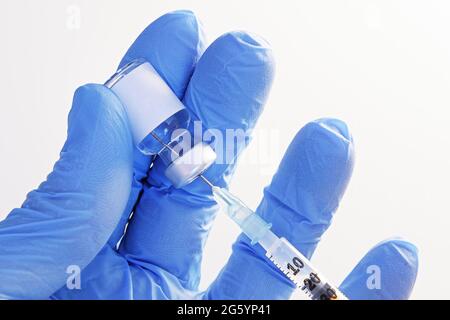 Gros plan de la main dans des gants tenant un flacon non marqué et en extrayant le liquide vers la seringue pour injection. Soins de santé, médecine, pharmacie et vaccination conc Banque D'Images