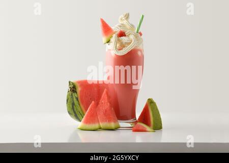 Milk-shake de pastèque à la crème décorée de fruits sur une table blanche et un fond isolé de lumière. Vue avant. Banque D'Images