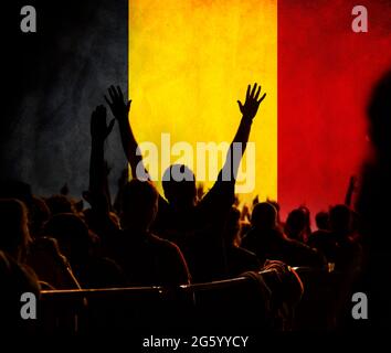 Les fans de football soutiennent la Belgique - la foule célèbre dans le stade avec des mains levées contre le drapeau de la Belgique Banque D'Images