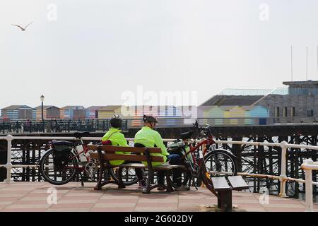 Hastings, East Sussex, Royaume-Uni. 01 juillet 2021. Météo au Royaume-Uni : des sorts ensoleillés pour la ville balnéaire de Hastings dans l'est du Sussex. Deux cyclistes se reposent sur un banc surplombant la mer. Crédit photo : Paul Lawrenson /Alay Live News Banque D'Images