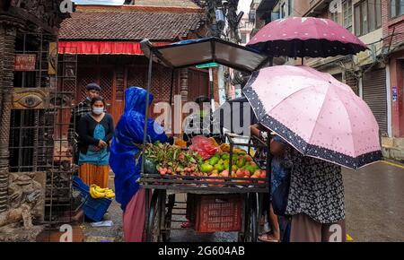 Katmandou, Bagmati, Népal. 1er juillet 2021. Les personnes sous parapluie achètent des fruits d'un vendeur de rue pendant les précipitations à Katmandou, Népal le 1er juillet 2021. Les fortes pluies laissent les népalais exposés à des inondations et à des glissements de terrain dans plusieurs régions du pays. Crédit : Sunil Sharma/ZUMA Wire/Alay Live News Banque D'Images