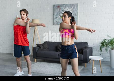 jeune couple de vêtements de sport s'échauffe avant de s'entraîner à la maison Banque D'Images