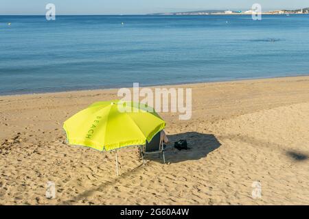 Personne méconnaissable sous un parapluie jaune sur une plage de l'île de Majorque au lever du soleil Banque D'Images