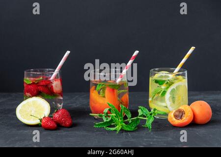 Trois différentes boissons saines d'été, limonade en verres avec paille sur fond noir. Gros plan. Banque D'Images