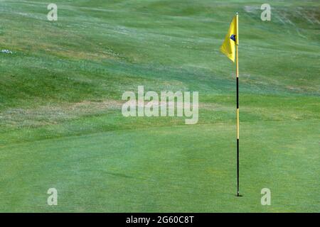 Un drapeau jaune sur un poteau dans un trou sur un terrain de golf Banque D'Images