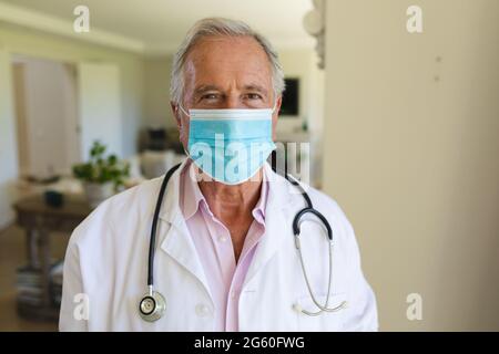 Portrait d'un médecin caucasien âgé portant un masque facial regardant l'appareil photo Banque D'Images