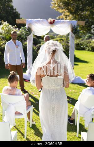 Bonne mariée caucasienne et marié se marient dans un jardin ensoleillé Banque D'Images