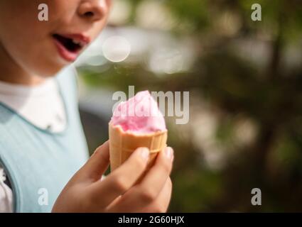 Glace rose dans une tasse à gaufres dans les mains des enfants. Banque D'Images
