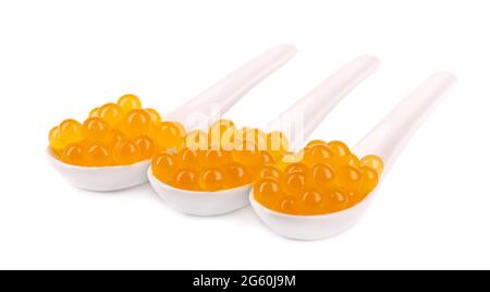 Perles de tapioca jaune pour le thé à bulles isolées sur fond blanc. Perles de tapioca dans une cuillère en céramique. Banque D'Images