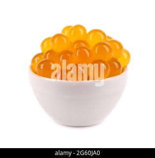 Perles de tapioca rouges pour le thé à bulles isolées sur fond blanc. Perles de tapioca en cuillère blanche en céramique. Banque D'Images