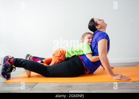 Garçon actif qui pose sur sa mère pendant qu'elle est debout en planche Banque D'Images