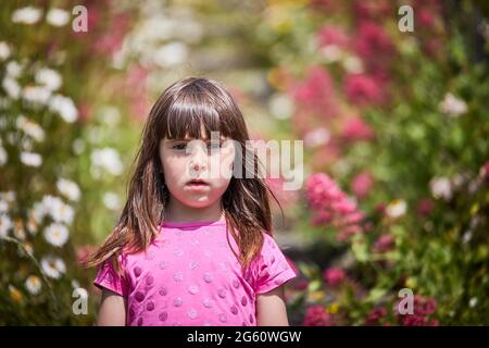 fille dans une robe rose entourée de fleurs dans la nature. Le garçon est debout sur quelques escaliers. Banque D'Images