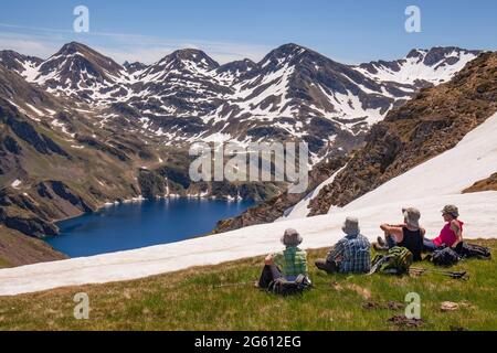 France, Hautes Pyrénées, quatre randonneurs bénéficient de la vue sur le Lac Bleu, depuis le Col de Bareilles (2238m). Banque D'Images