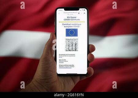 Un certificat COVID de l'UE est vu sur un appareil mobile avec un drapeau letton en arrière-plan dans cette illustre photo à Varsovie, en Pologne, le 1er juillet 20 Banque D'Images