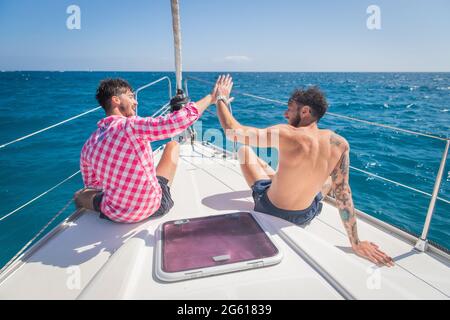 deux amis sur un bateau sont heureux et font haut cinq, la journée est belle, le ciel est clair et ils apprécient la vie. Concept d'amitié. Banque D'Images