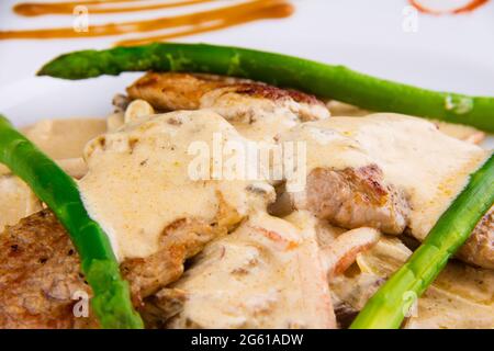 Médaillons de porc aux asperges : filet de porc, asperges, champignons, poireaux, oignons, carottes et sauce demi-glace. Banque D'Images