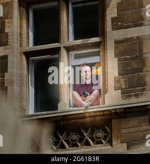 L'étudiant est assis sur une bordure de fenêtre pour photographier les étudiants de premier cycle lors de leur journée de remise des diplômes à Gonville et Caius College, université de Cambridge, Angleterre, 1er juillet 2021. Banque D'Images