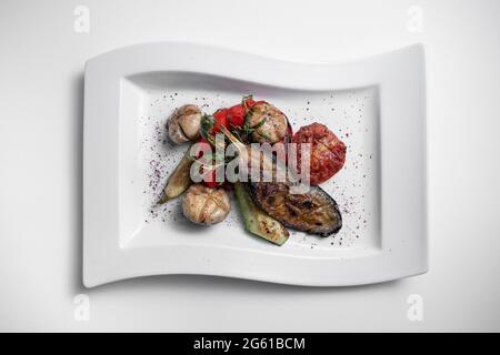 vue de dessus des légumes grillés et du champaignon sur une assiette blanche sur fond blanc Banque D'Images