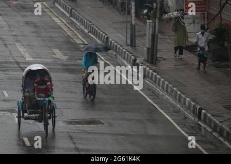 Dhaka, Bangladesh. 1er juillet 2021. Des gens ont vu se déplacer sur une route déserte au milieu de la pluie de mousson à Dhaka.le gouvernement du Bangladesh a annoncé un nouveau confinement pour contenir la propagation du coronavirus Covid-19 au Bangladesh. Crédit : SOPA Images Limited/Alamy Live News Banque D'Images