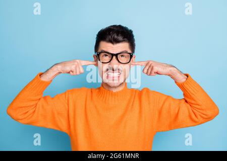 Photo de fureur négatif beau gars grind dents doigts fermer les oreilles regarder vers le haut vide espace isolé sur fond bleu de couleur Banque D'Images