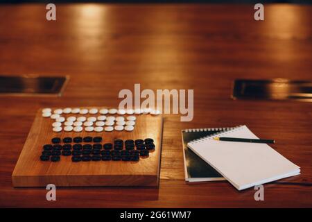 Weichi le jeu de Go se trouve sur la table avec un bloc-notes blanc et un stylo Banque D'Images