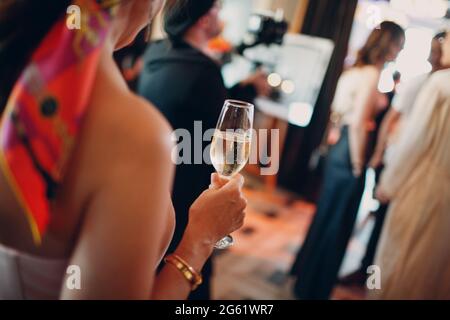 vue arrière femme tenant un verre de champagne frais embué à la main à la fête. Banque D'Images