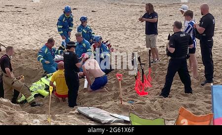 Newquay, Royaume-Uni. 1er juillet 2021. Newquay, Cornwall, Fistral Beach. 18:00 heures. Un homme de vacances a été englouti par le sable quand un trou profond creusé dans la plage de sable lâche s'est effondré l'enterrant. Les amateurs de plage et les sauveteurs ont creusé frénétiquement jusqu'à l'arrivée des équipes de garde-côtes et de secours des pompiers. On pense que la victime a subi des blessures par écrasement et que l'oxygène découvert a été fourni sous forme de canisters. Un membre du garde-côtes est vu appliquer un goutte-à-goutte à la victime. Les quatre services d'urgence ont assisté à l'incident. 1er juillet 2021. Crédit : Robert Taylor/Alay Live News Banque D'Images