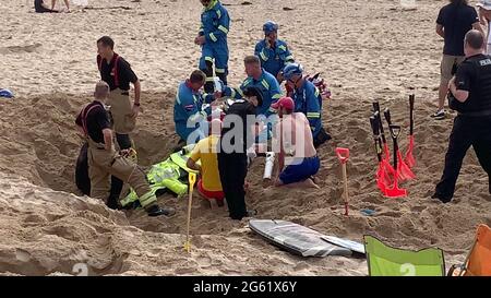 Newquay, Royaume-Uni. 1er juillet 2021. Newquay, Cornwall, Fistral Beach. 18:00 heures. Un homme de vacances a été englouti par le sable quand un trou profond creusé dans la plage de sable lâche s'est effondré l'enterrant. Les amateurs de plage et les sauveteurs ont creusé frénétiquement jusqu'à l'arrivée des équipes de garde-côtes et de secours des pompiers. On pense que la victime a subi des blessures par écrasement et que l'oxygène découvert a été fourni sous forme de canisters. Un membre du garde-côtes est vu appliquer un goutte-à-goutte à la victime. Les quatre services d'urgence ont assisté à l'incident. 1er juillet 2021. Crédit : Robert Taylor/Alay Live News Banque D'Images