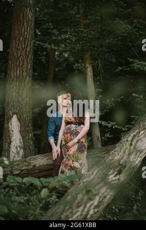 Grossesse, concept de parentalité. Heureux couple enceinte, debout dans la belle forêt d'été, embrassant et souriant les uns les autres Banque D'Images