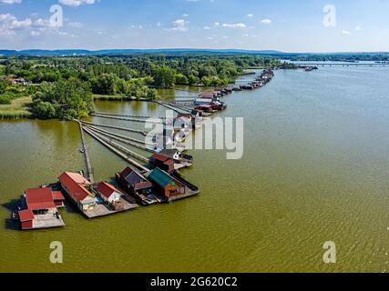 Vue aérienne du célèbre village flottant de Bokod avec jetées et chalets de pêche traditionnels en bois construits sur le lac de Bokodi. Banque D'Images